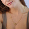 Gold necklace worn by a person with a neutral background